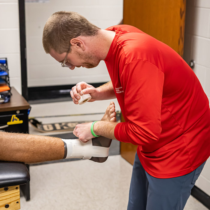 physical therapist taping up clients ankle